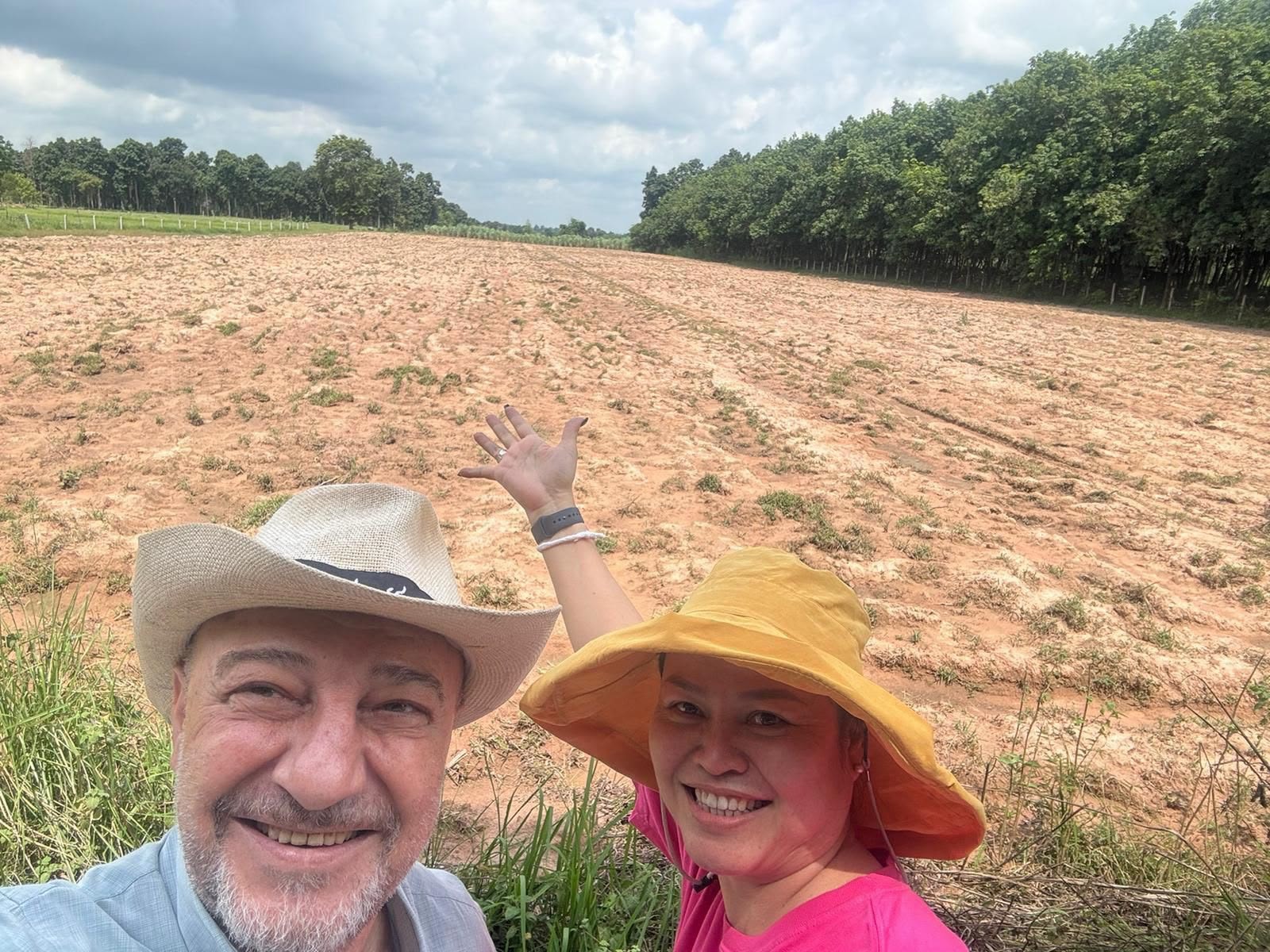 Armen and Jiratchaya standing together in front of the prepared Magic Land field, smiling and gesturing toward the land